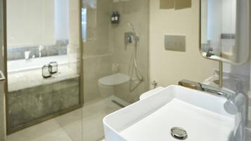 Un baño moderno con un lavamanos grande y blanco, ducha con cerramiento de vidrio y espejo con toallero.