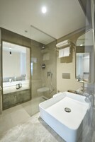 Un baño moderno con un lavamanos grande y blanco, ducha con cerramiento de vidrio y espejo con toallero.