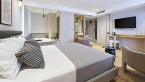 Habitació d'hotel moderna amb un llit gran, televisió, bany amb banyera i zona de seients.