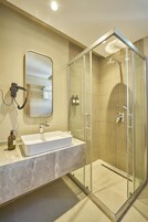 Un baño con ducha de vidrio, lavamanos blanco y espejo.