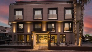 Un edifici modern d'alguns pisos amb balcons, grans finestres i una entrada ben il·luminada.