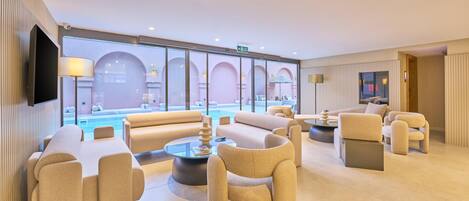A modern lobby with a pool view, comfortable seating, and a flat-screen TV.