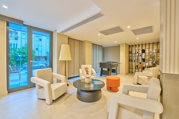 Una sala de estar moderna con una mesa de centro de vidrio, sofás blancos, una lámpara y vistas al exterior.
