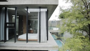 Une chambre moderne avec une cloison en verre, un lit et une vue sur une piscine.