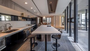 Une cuisine moderne dotée d’un grand îlot central, de tabourets de bar et d’un coin repas avec une table et des chaises.