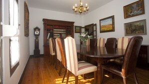 A dining room with a wooden table surrounded by striped chairs, a chandelier, and framed artwork on the walls. - Villa Victoria (AS)