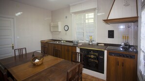 A kitchen with wooden cabinets, a dining table, and a built-in oven. - Villa Victoria (AS)