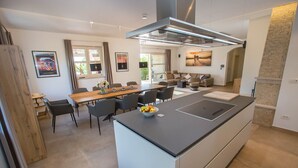 Una cocina moderna con una isla central, comedor con sillas y un sofá al fondo.
