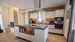 Una cocina moderna con una isla central, electrodomésticos integrados y una pared de acento de piedra.