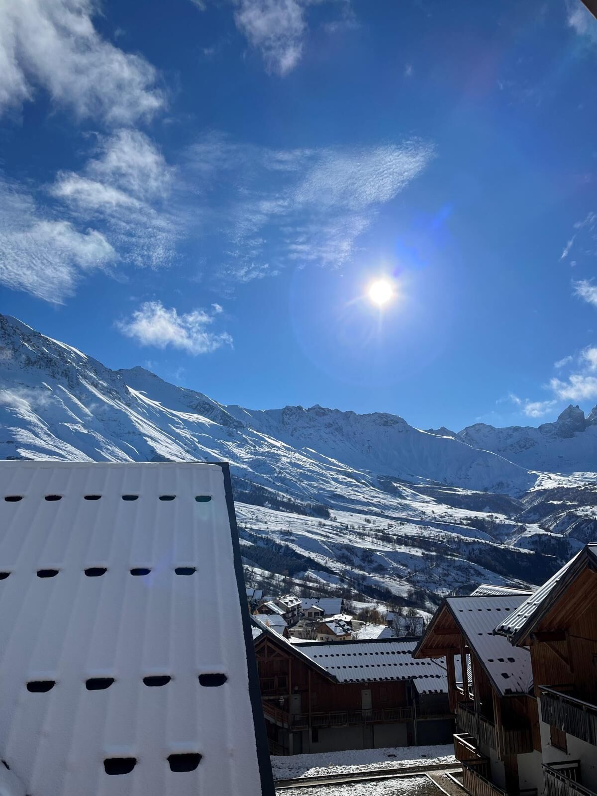 A mountain view with a chalet-style building, a snow-covered landscape, and a clear sky.