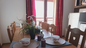 Ein Esstisch, gedeckt mit zwei weißen Tassen, einer Topfpflanze und Kerzen.
