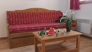 Ein Holztisch mit einem roten, gemusterten Sofa und einer Topfpflanze in der Ecke.