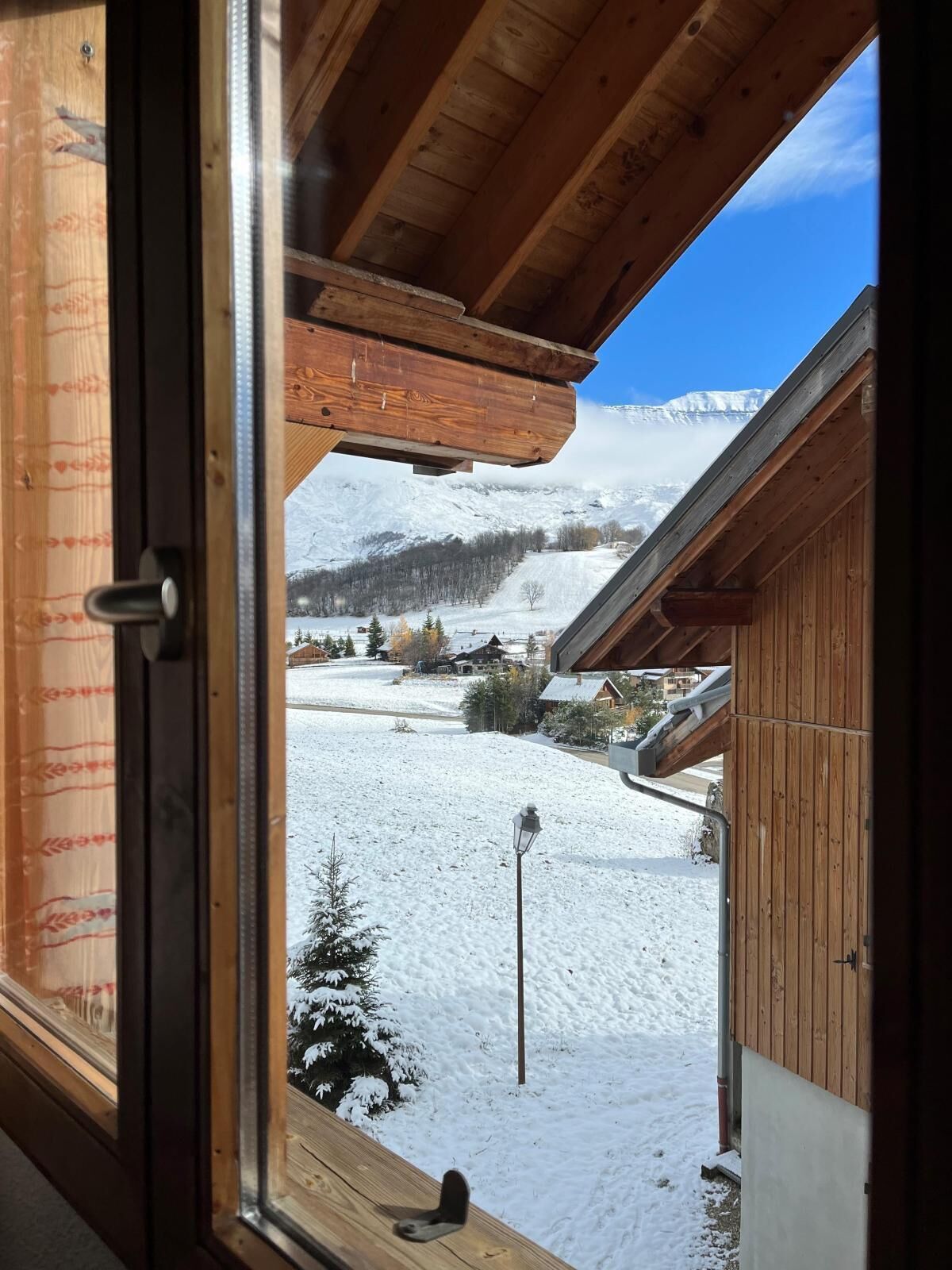 A wooden cabin with a view of a snowy landscape and mountains.