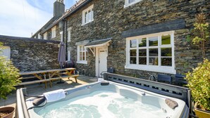 Un bâtiment en pierre avec un jacuzzi, une table en bois et un banc.