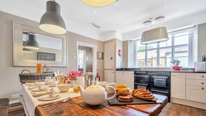 A kitchen with a wooden table set for breakfast, a large mirror, and a view of the outside. - Alice Howe - a big house with hot tub and cinema for groups to get together in the Lake District. (Windermere)