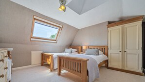 A bedroom with a sloped ceiling, a skylight, a wooden bed, bedside tables, a wardrobe, and a dresser. - Alice Howe - a big house with hot tub and cinema for groups to get together in the Lake District. (Windermere)