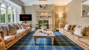 Un soggiorno con camino, divani in pelle, un tavolino da caffè e una televisione che mostra 'NETFLIX'.
