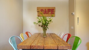 A wooden dining table with colorful chairs, a vase with flowers, and a 'CAFE' sign on the wall. - Orrest Head Cottage,  located on the footpath to the famous Orrest Head walk. Perfect for dog walks. (Windermere)