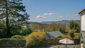 A patio with outdoor seating, a stone wall, and a view of distant mountains. - Orrest Head Cottage,  located on the footpath to the famous Orrest Head walk. Perfect for dog walks. (Windermere)