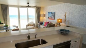 A modern kitchen with a large island, a built-in dishwasher, and a view of the ocean. - Pelican Beach 0701 2 Bedroom Home (Destin)