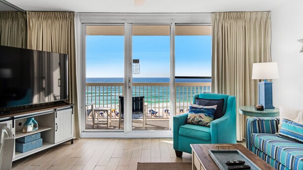 A living room with a TV, teal armchair, and a sofa with striped cushions.