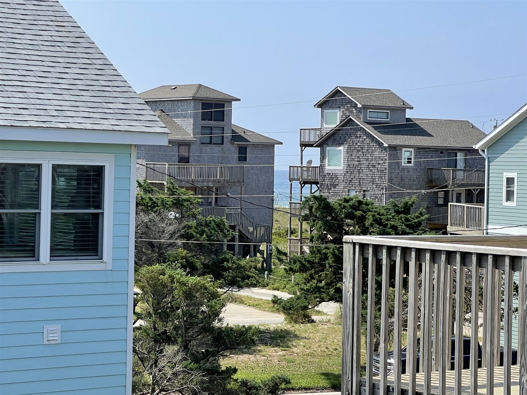 A coastal residential area with multiple two-story houses featuring balconies and a wooden deck.