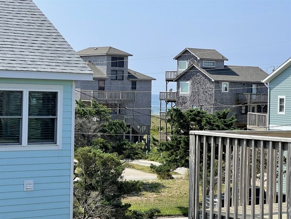 A coastal residential area with multiple two-story houses featuring balconies and a wooden deck. - Swinkels 3 Bedroom Cottage by RedAwning (Frisco)