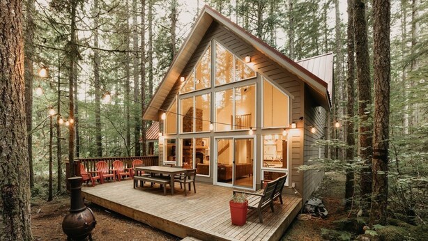 A cabin with a deck, large windows, and a fireplace. - 40gs â Wifi - W/d â Hot Tub - Sleeps 8 3 Bedroom Cabin by RedAwning (Deming)