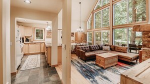 A spacious living area with a large window, a wooden coffee table, and a sofa. - 40gs â Wifi - W/d â Hot Tub - Sleeps 8 3 Bedroom Cabin by RedAwning (Deming)