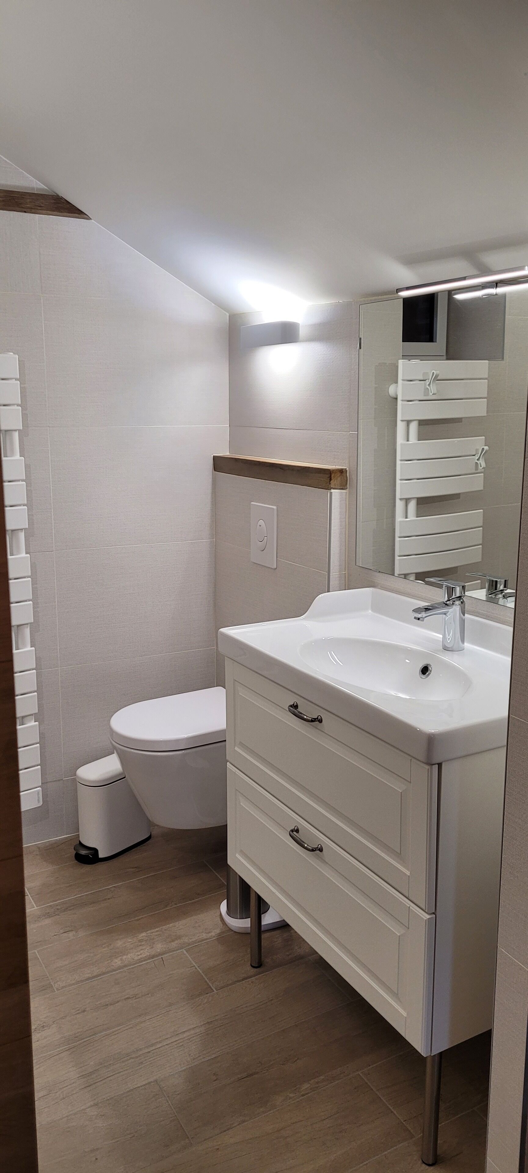 Un baño moderno con lavamanos, espejo y váter blancos.