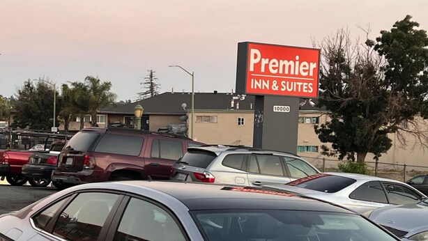 A parking lot with several cars and a sign for Premier Inn & Suites.