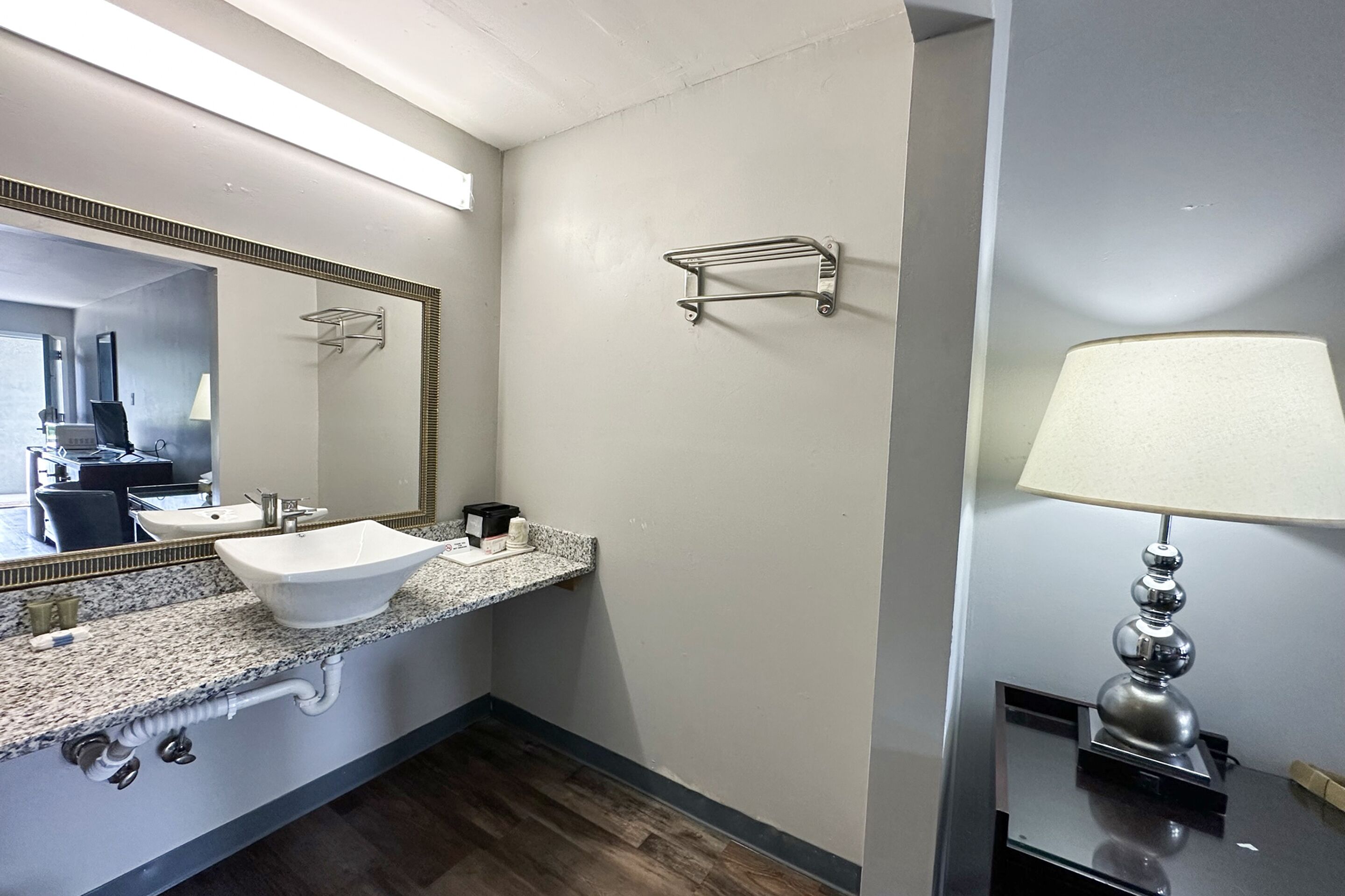Un baño con lavamanos blanco, espejo, toallero y lámpara.