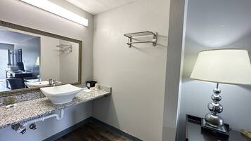 Un baño con lavamanos blanco, espejo, toallero y lámpara.