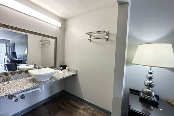 A bathroom with a white sink, a mirror, a towel rack, and a lamp.