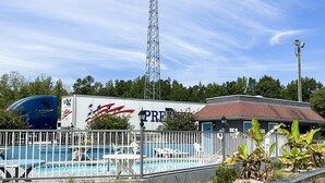A hotel with a swimming pool, outdoor seating, and a large billboard.