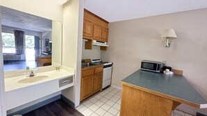 A compact kitchen with a sink, stove, microwave, and wooden cabinets.