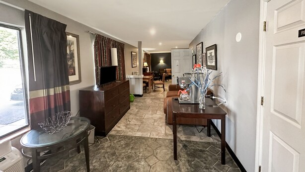 A spacious living area with a large window, a television, a dining table, and a coffee table.