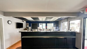 A reception area with a counter, a clock, and a window with a view of the outside.