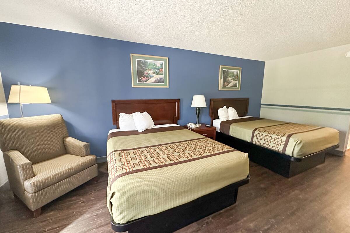 A hotel room with two beds, a sofa, and two lamps.