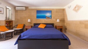 Ein Schlafzimmer mit einem Bett, zwei Nachttischen, zwei Lampen, einem Sessel und einem Bild eines Bootes an der Wand.