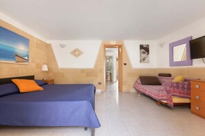 Ein Schlafzimmer mit einem Bett, einem Schlafsofa, einem Schminktisch und einem Fernseher.