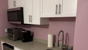A modern kitchen with white cabinets, a stainless steel sink, a microwave, and a dishwasher.