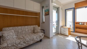 A modern living room with a sofa, a wooden cabinet, a small table, and a view of the outside. - 3500 Panorama D`otranto by Barbarhouse (Otranto)