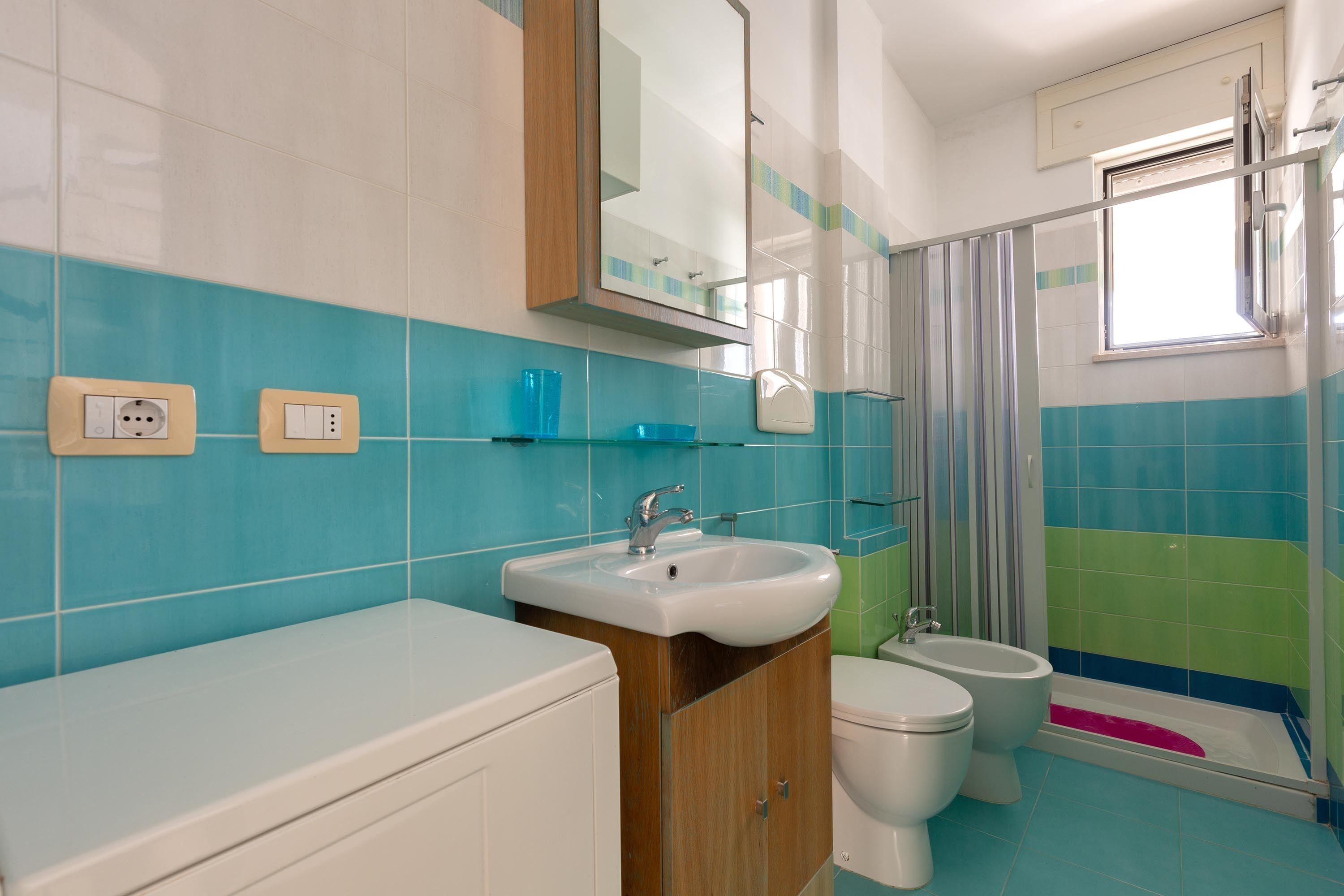 A bathroom with a sink, two toilets, a bidet, and a shower.