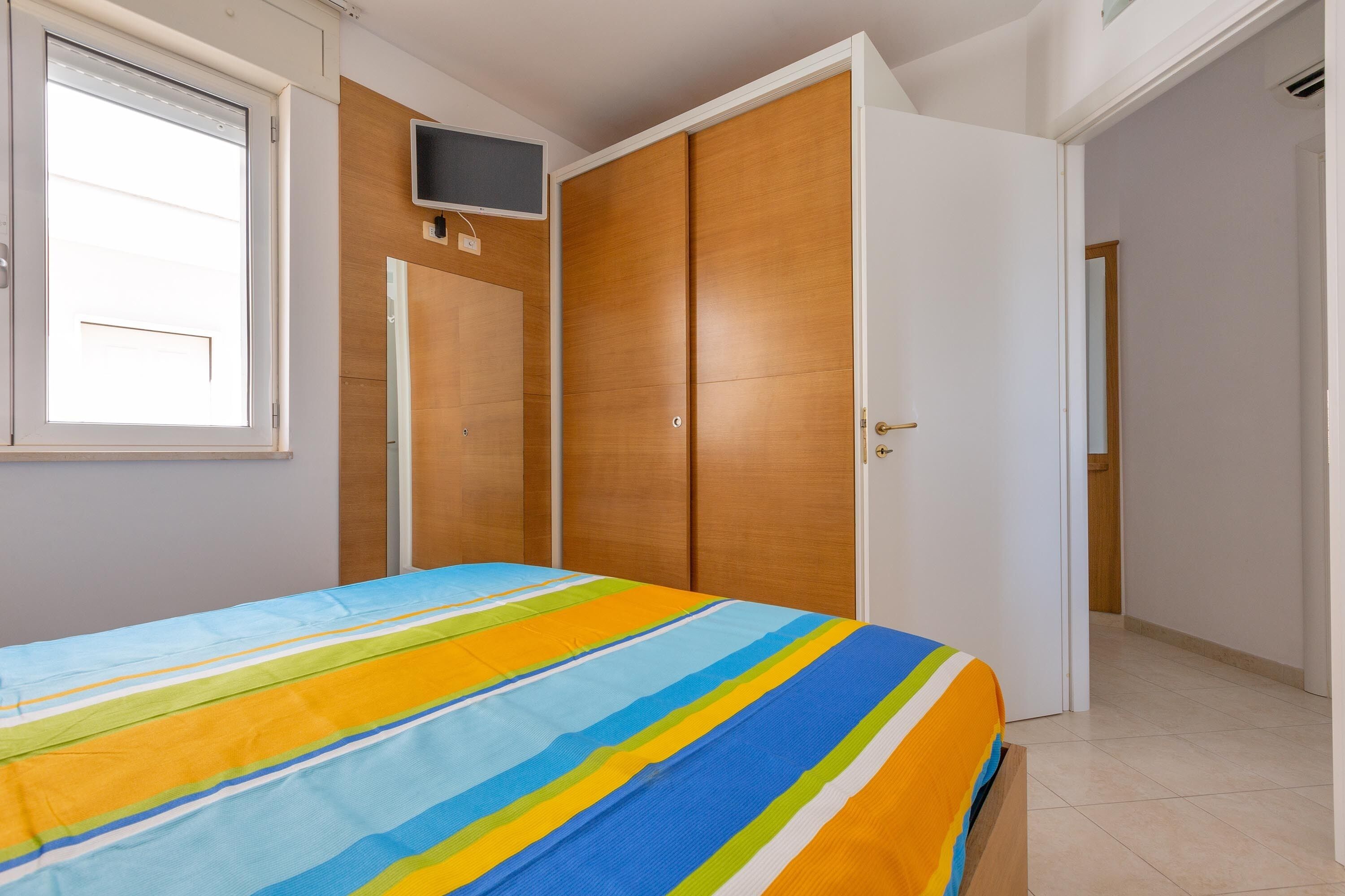 Une chambre à coucher avec un lit, un téléviseur fixé au mur et une armoire.
