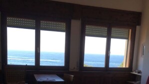 Ein Zimmer mit Meerblick, einem Holztisch, einem roten Sofa und einem gemusterten Teppich.