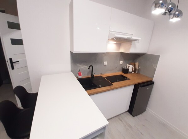 A modern kitchen with a white countertop, black sink, and a dishwasher. - Souvenirappart Sienkiewicza 3E (Bydgoszcz)