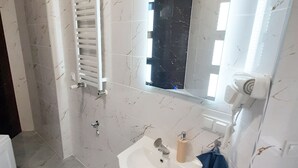 Un baño con lavabo blanco, espejo y perchero para toallas.