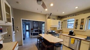 Una cocina moderna con una isla central, estufa y pileta. Se puede ver un ventilador de techo, alacenas y un bote de basura.