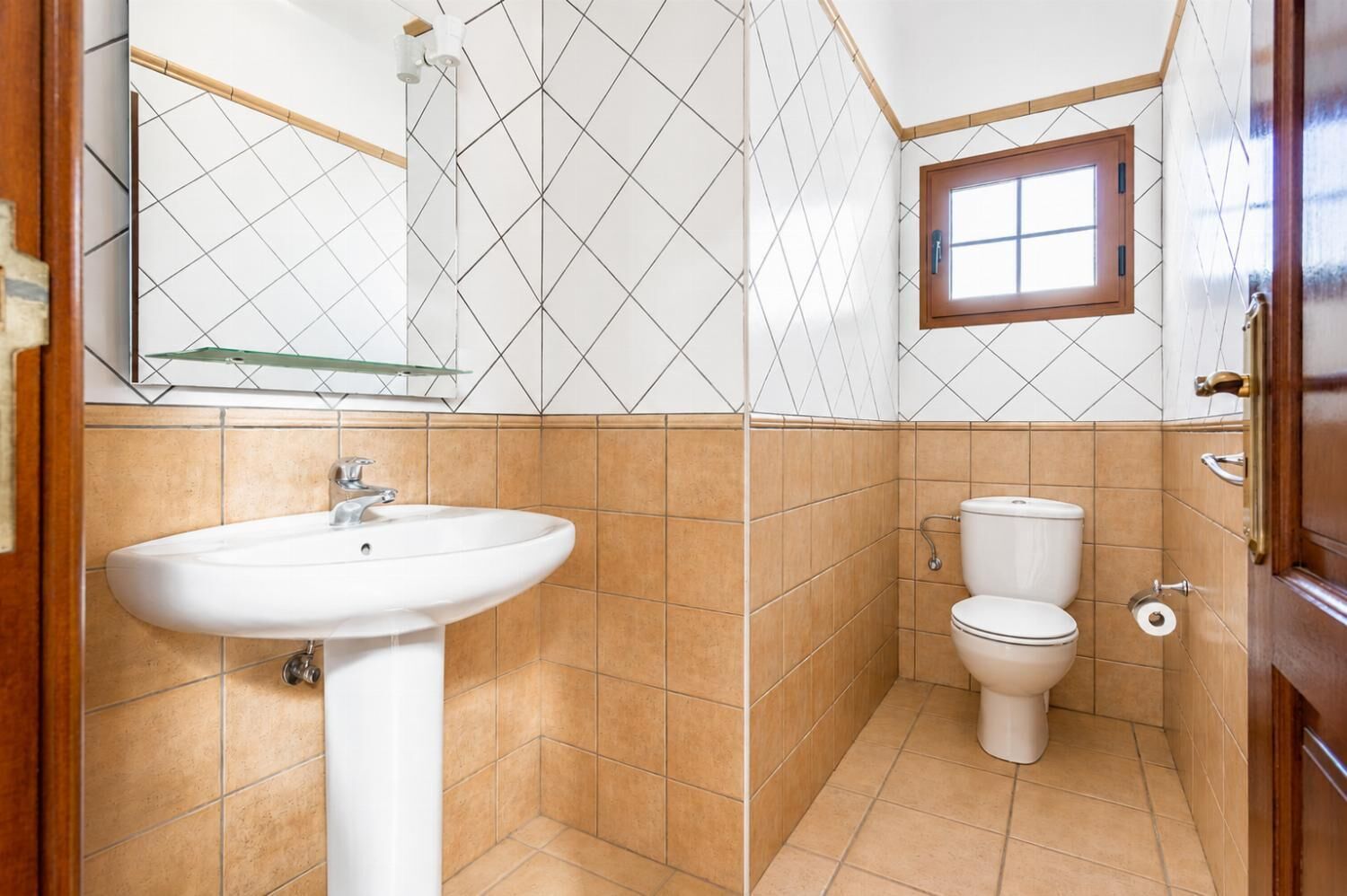 Ein Badezimmer mit einem weißen Waschbecken, einer Toilette und einem Fenster.